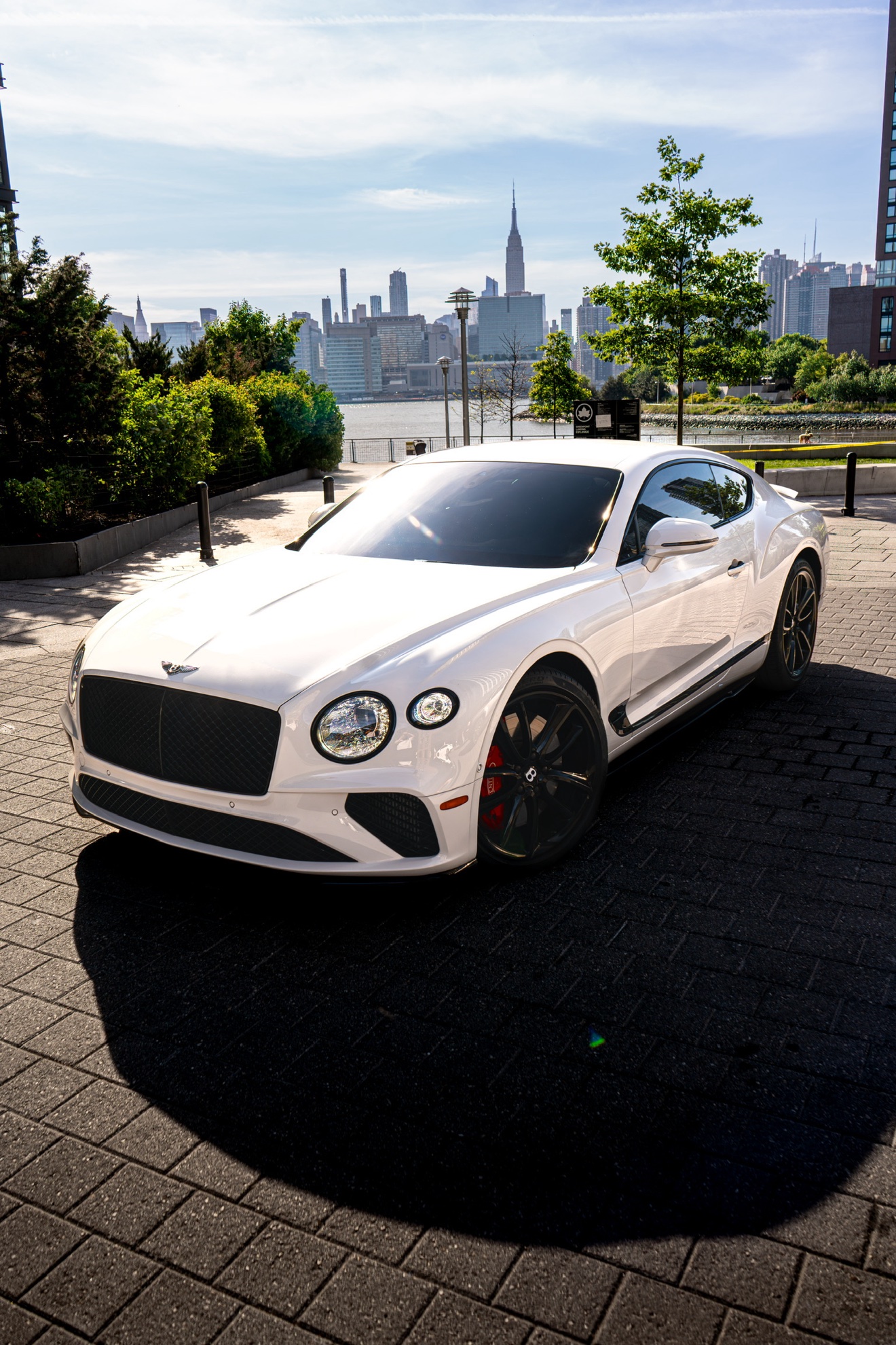 White Bentley Continental GT Coupe shown from the front three-quarter angle by the Manhattan skyline
