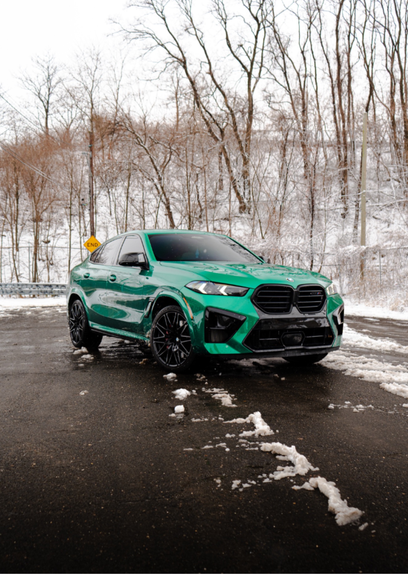 Green 2025 BMW X6 M Competition shown from the front three-quarter angle on a snowy road