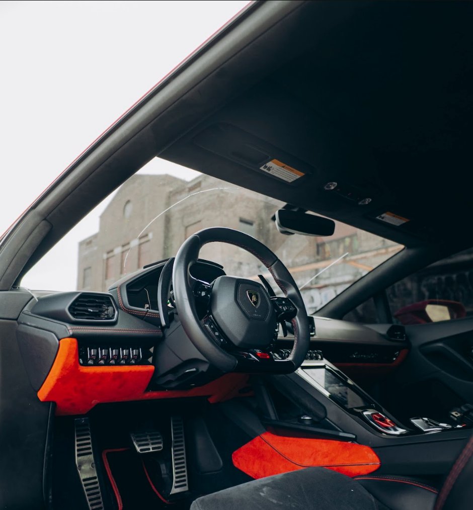 Driver cockpit and steering wheel of the red Lamborghini Huracán Evo with red and black interior