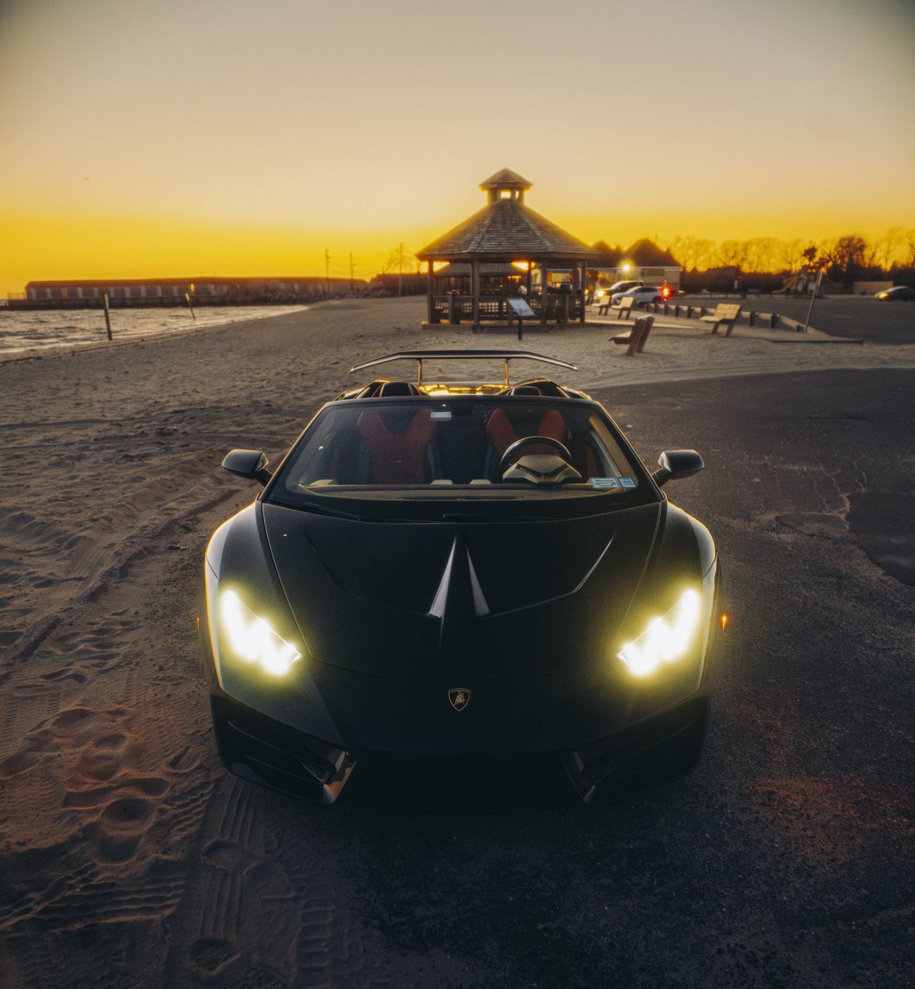 Front view of the black Lamborghini Huracán Evo Spyder with the top down at sunset
