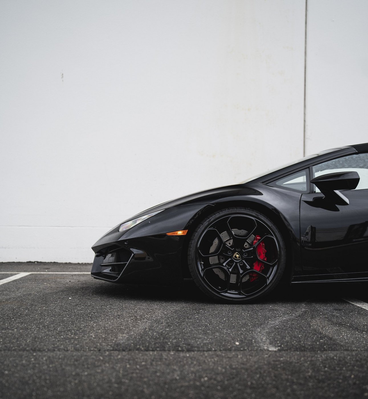 Front wheel and red brake caliper detail of the black Lamborghini Huracán Evo Spyder