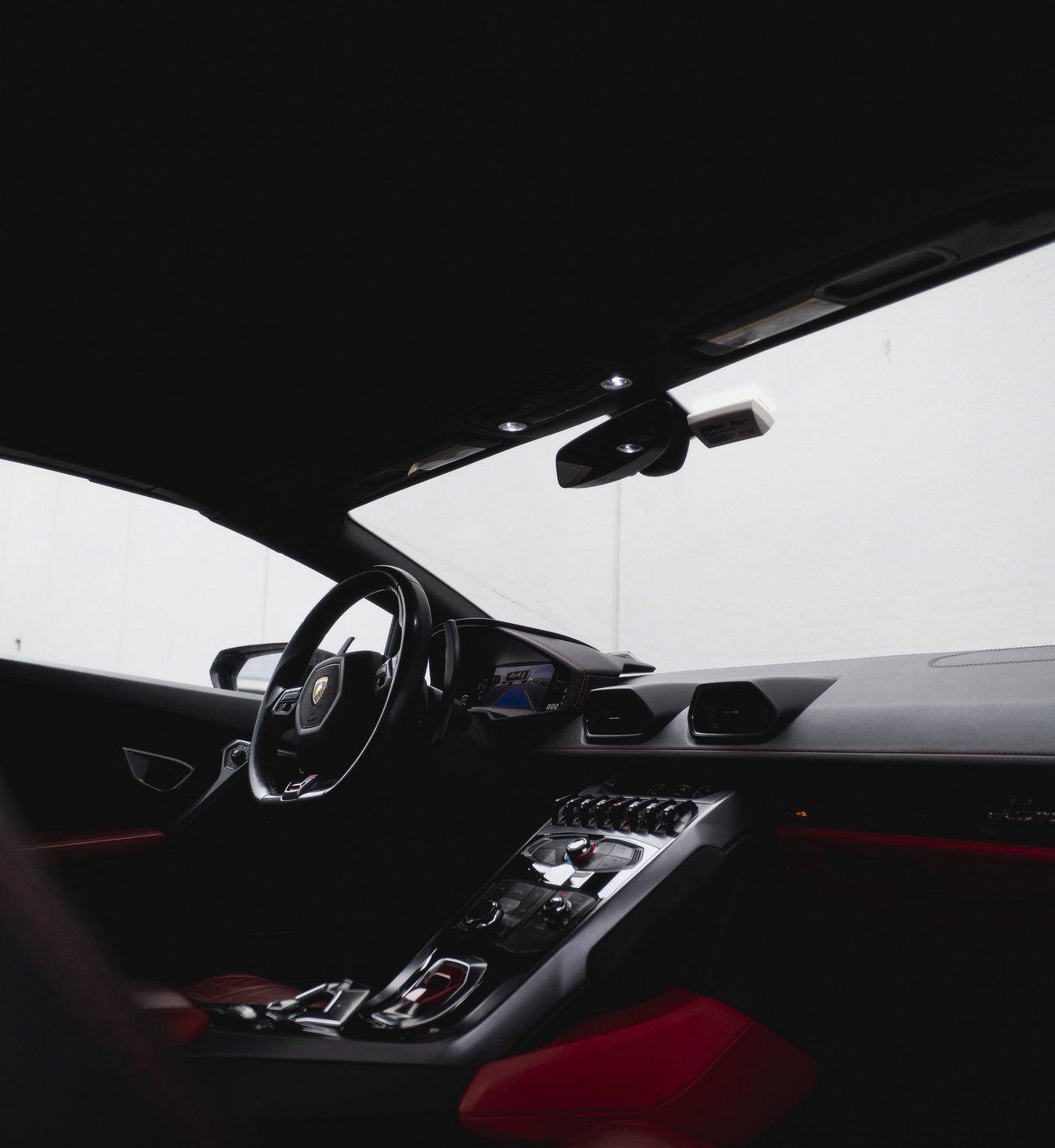 Cockpit, dashboard, and center console of the black Lamborghini Huracán Evo Spyder with red and black interior