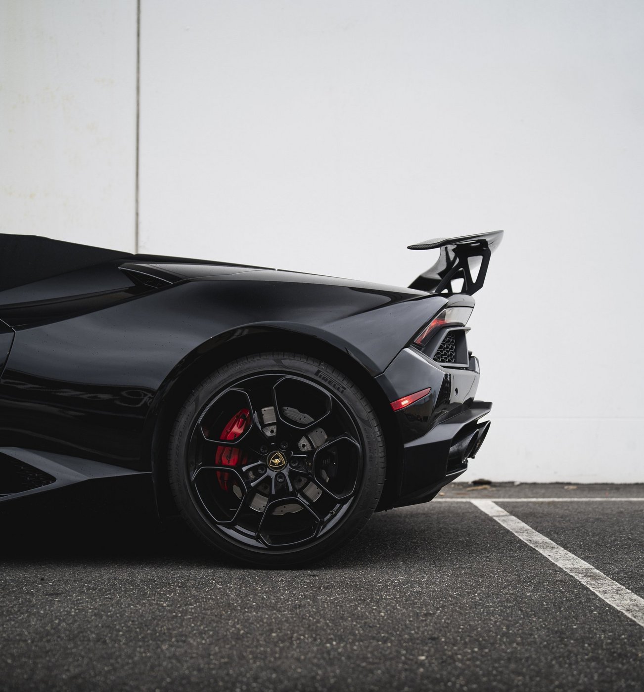 Rear wheel and rear wing detail of the black Lamborghini Huracán Evo Spyder