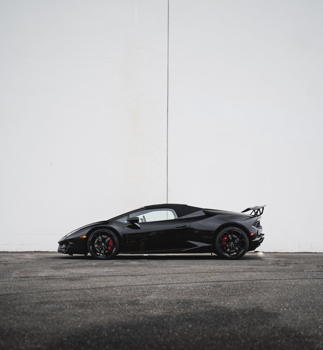 Side profile of the black Lamborghini Huracán Evo Spyder with the soft top up