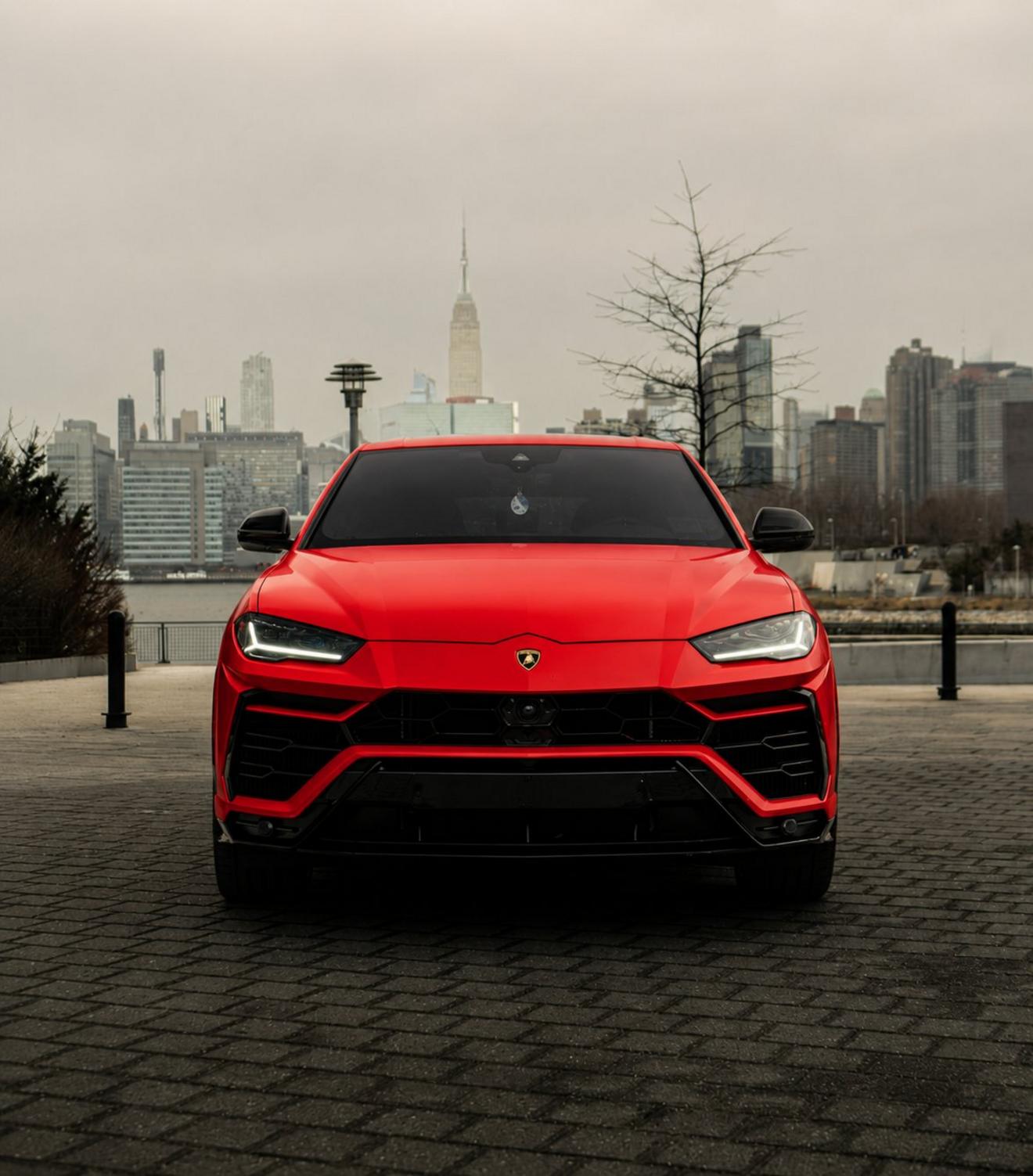 Red Lamborghini Urus shown from the front with the Manhattan skyline