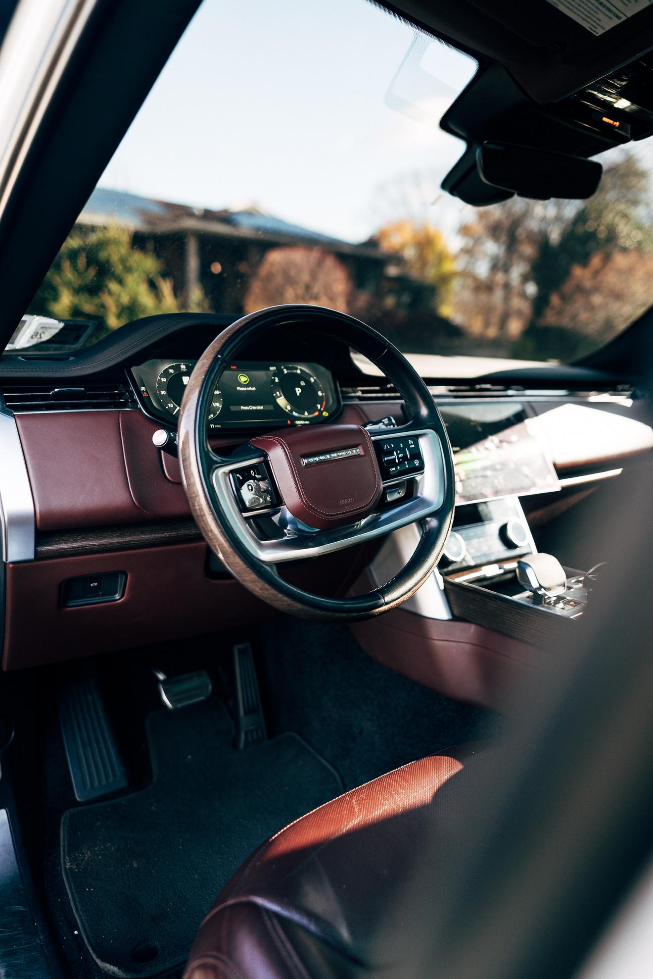 Driver cockpit and steering wheel of the Range Rover with red interior